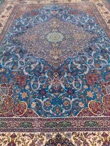 Azerbaijan Tappeti Milano Tappeto persiano decorato con intricati motivi floreali e un logo colorato nell'angolo in alto a destra.