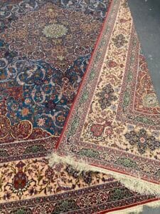 Azerbaijan Tappeti Milano Due tappeti in stile persiano con motivi intricati, su sfondi blu scuro e crema, caratterizzati da motivi floreali e geometrici.