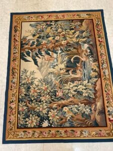 Azerbaijan Tappeti Milano Tappeto rettangolare in stile arazzo con una scena di natura con uccelli, alberi e fiori, delimitata da un motivo floreale. Il tappeto presenta colori ricchi e tenui e dettagli intricati, adagiato su un pavimento piastrellato chiaro.