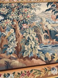 Azerbaijan Tappeti Milano Un arazzo decorativo raffigura un albero con grandi foglie e fiori, due anatre che nuotano in uno stagno e un fogliame rigoglioso. Nell'angolo in alto a destra si trova un colorato disegno astratto di foglie.