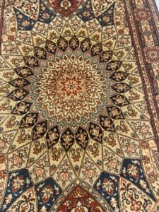 Azerbaijan Tappeti Milano Tappeto persiano ornato con un intricato motivo geometrico e floreale simmetrico nei toni del crema, del marrone, del blu e del rosso, con un fiore colorato e un logo aggiunto nell'angolo superiore destro.
