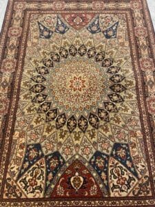 Azerbaijan Tappeti Milano Tappeto persiano tradizionale caratterizzato da un intricato medaglione centrale con motivo a stella e disegni floreali e geometrici nei toni del rosso, blu, beige e marrone. Nell'angolo in alto a destra si trova il logo di una farfalla colorata.