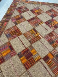 Azerbaijan Tappeti Milano Un tappeto multicolore in stile patchwork con motivi geometrici quadrati è steso in piano.