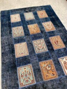 Azerbaijan Tappeti Milano Un tappeto con motivi quadrati blu scuro, caratterizzato da intricati motivi floreali e geometrici nelle tonalità del marrone, blu e beige.