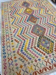 Azerbaijan Tappeti Milano Tappeto intrecciato colorato con motivi geometrici e forme di diamante in varie tonalità su sfondo beige.