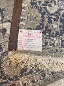 Azerbaijan Tappeti Milano Tappeto con bordo a frange e angolo in pelle. Un'etichetta riporta dettagli su origine, qualità, composizione e dimensioni in italiano. C'è un logo colorato nell'angolo in alto a destra.