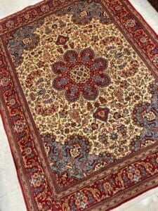 Azerbaijan Tappeti Milano Un tappeto persiano rettangolare con intricati motivi floreali nei toni del rosso, del blu e del beige. Presenta un medaglione centrale e un bordo rosso.