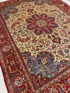 Azerbaijan Tappeti Milano Un tappeto persiano dettagliato con intricati motivi floreali e geometrici nei toni del rosso, del blu e del beige. Presenta un medaglione centrale e un bordo decorativo.