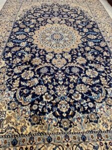 Azerbaijan Tappeti Milano Un tappeto persiano blu e beige dal motivo intricato, con un dettagliato medaglione centrale, adagiato orizzontalmente.