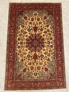 Azerbaijan Tappeti Milano Tappeto ornato in stile persiano con medaglione centrale e intricati motivi botanici in rosso, beige e nero. Un logo colorato è nell'angolo in alto a destra.