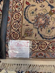 Azerbaijan Tappeti Milano Primo piano di un tappeto orientale tradizionale con intricati motivi floreali, con un'etichetta che ne indica l'origine, la qualità, le dimensioni e il prezzo. Il bordo e le frange del tappeto sono visibili in basso.