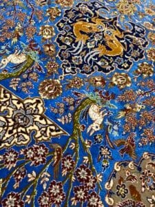Azerbaijan Tappeti Milano Intricato tappeto persiano con sfondo blu, decorato con motivi floreali, creature mitologiche e un disegno astratto multicolore in un angolo.