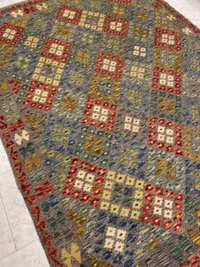 Azerbaijan Tappeti Milano Tappeto colorato con motivi geometrici, composto da un mix di quadrati e triangoli nei toni del rosso, del blu, del giallo e del verde su uno sfondo multicolore.