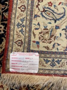 Azerbaijan Tappeti Milano Primo piano di un angolo di tappeto con un motivo floreale dettagliato. Un'etichetta bianca mostra informazioni in italiano sull'origine, la qualità, il materiale, le dimensioni e il numero di serie del tappeto.