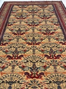 Azerbaijan Tappeti Milano Tappeto a fantasia con intricati disegni geometrici e floreali in rosso, blu, verde e beige. Il tappeto presenta un bordo dettagliato e un logo a foglie e volute colorate nell'angolo in alto a destra.