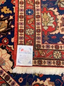 Azerbaijan Tappeti Milano Primo piano di un tappeto azero decorato, di cui si vedono le frange e un'etichetta con dettagli scritti a mano nell'angolo in basso a sinistra.