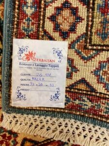 Azerbaijan Tappeti Milano Primo piano dell'etichetta di un tappeto con la scritta "Azerbaijan" e dettagli sul cliente, sulla qualità e sulle misure.