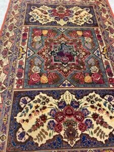 Azerbaijan Tappeti Milano Tappeto decorato in stile persiano con motivi floreali e un logo raffigurante un uccello colorato nell'angolo in alto a destra.