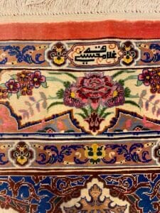 Azerbaijan Tappeti Milano Primo piano di un tappeto persiano decorato con motivi floreali e una scritta decorativa al centro.