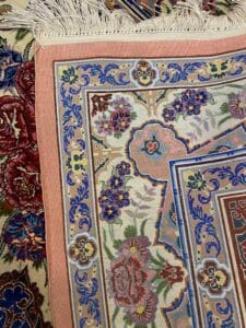 Azerbaijan Tappeti Milano Primo piano di un tappeto intrecciato colorato con motivi floreali, frange e intricati disegni sui bordi.