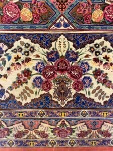 Azerbaijan Tappeti Milano Intricato tappeto persiano con motivi floreali nei toni del rosso, blu e crema e un colorato motivo a stella in un angolo.