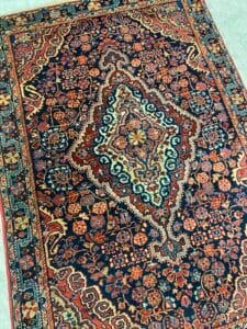 Azerbaijan Tappeti Milano Tappeto persiano vintage con intricati motivi floreali e geometrici nei toni del rosso, blu, crema e arancione.