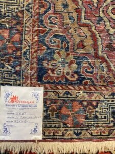 Azerbaijan Tappeti Milano Primo piano di un tappeto decorato con etichetta recante la scritta “Azerbaijan” e dettagli del restauro scritti a mano.