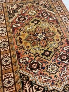 Azerbaijan Tappeti Milano Un tappeto persiano decorato con intricati disegni geometrici nei toni del marrone, del giallo e del rosso.