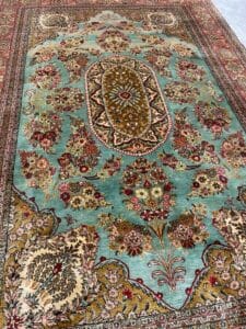 Azerbaijan Tappeti Milano Tappeto con motivi floreali intricati, sfondo verde acqua e decorati motivi rossi, dorati e beige.