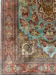 Azerbaijan Tappeti Milano Primo piano di un tappeto persiano decorato con motivi floreali nei colori verde acqua, rosso e beige.
