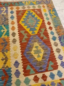 Azerbaijan Tappeti Milano Tappeto colorato con motivi geometrici a forma di rombi e bordi a zigzag nei toni del rosso, giallo, blu e verde.