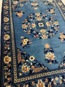 Azerbaijan Tappeti Milano Tappeto orientale blu con motivi floreali e medaglione centrale; logo a forma di farfalla colorata nell'angolo.