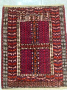 Azerbaijan Tappeti Milano Tappeto con motivi geometrici rossi e arancioni e una farfalla colorata nell'angolo in alto a destra.