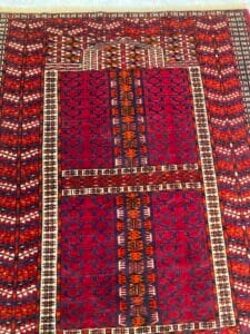 Azerbaijan Tappeti Milano Tappeto rosso con motivi geometrici, motivo rettangolare centrale e una foglia multicolore in un angolo.